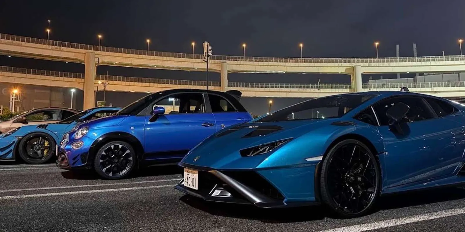 Blue Lamborghini Huracan parked alongside other tuned cars at a Tokyo meet
