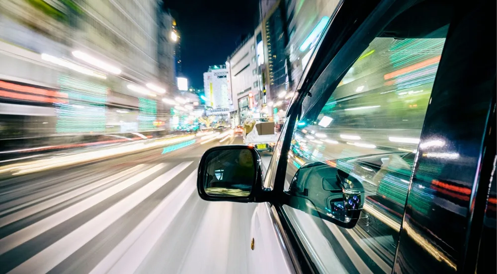 View from inside the pickup vehicle weaving through Tokyo's neon-lit streets at night