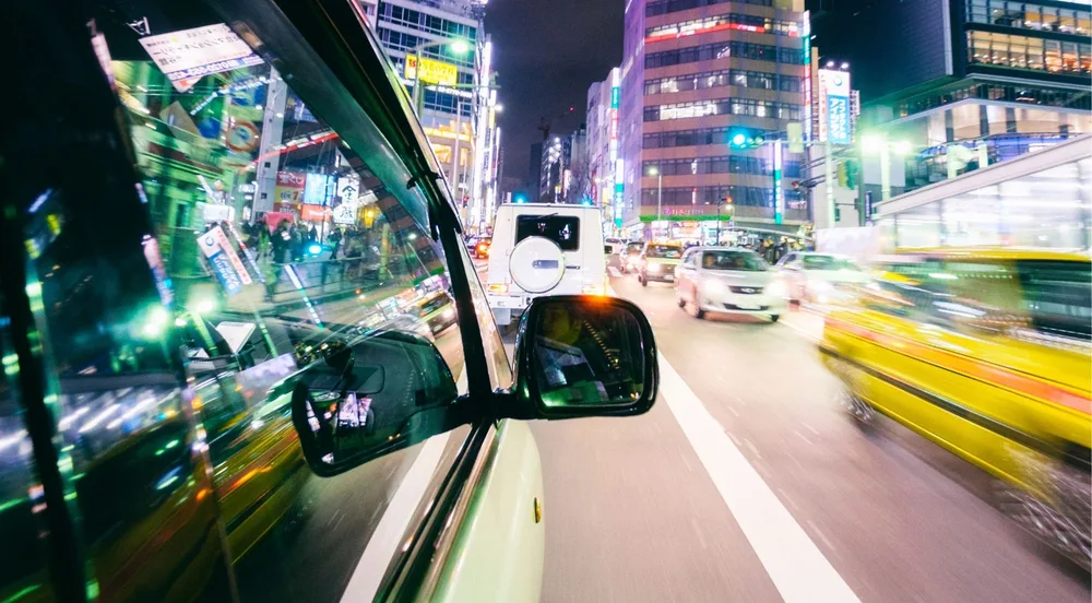 Tokyo intersection ablaze with neon signs, seen from the car during the night drive