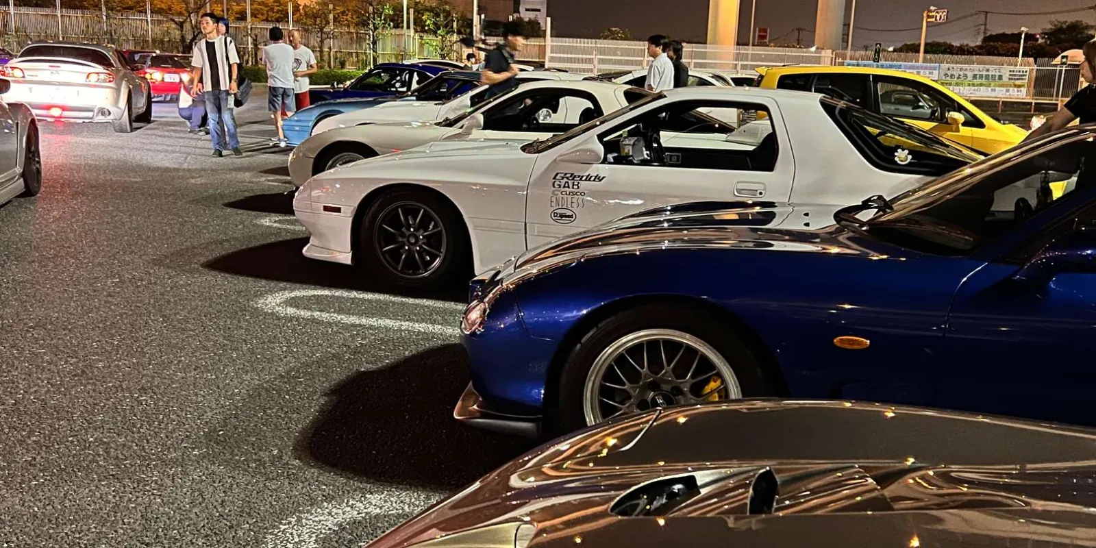 Row of modified Mazda RX-7s and other JDM sports cars lined up at a Tokyo meet-up