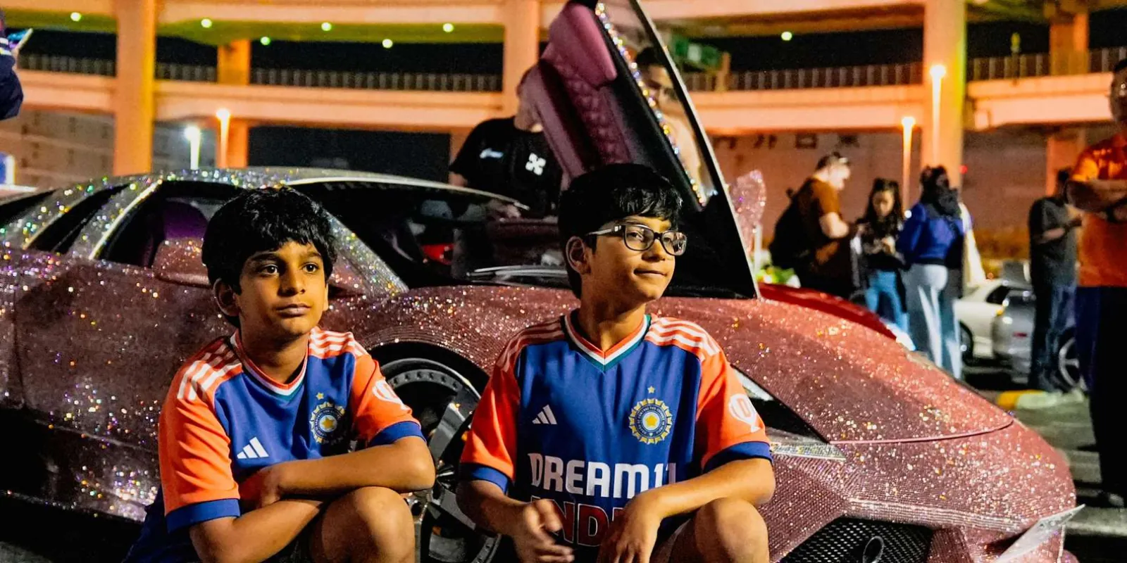 Young car-culture fans posing beside a rhinestone-wrapped pink Lamborghini at the meet